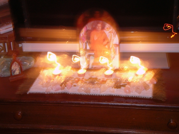 photo of altar after reading given by Comic Sai Baba. Photo shows three leelas with om symbol, Baba rising from photo and light circles around tea-lights